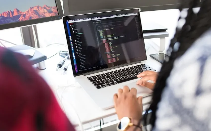 Seorang insinyur IT sedang bekerja di depan beberapa monitor.