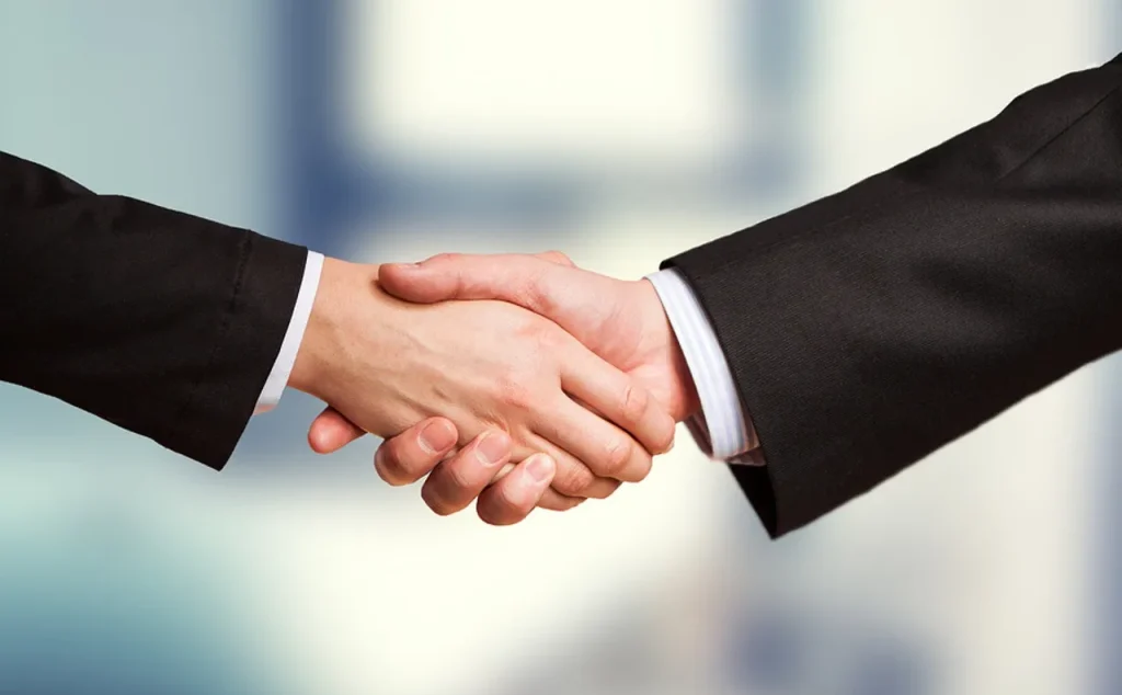 Jabat tangan antara dua perwakilan negara, melambangkan kerja sama bilateral.