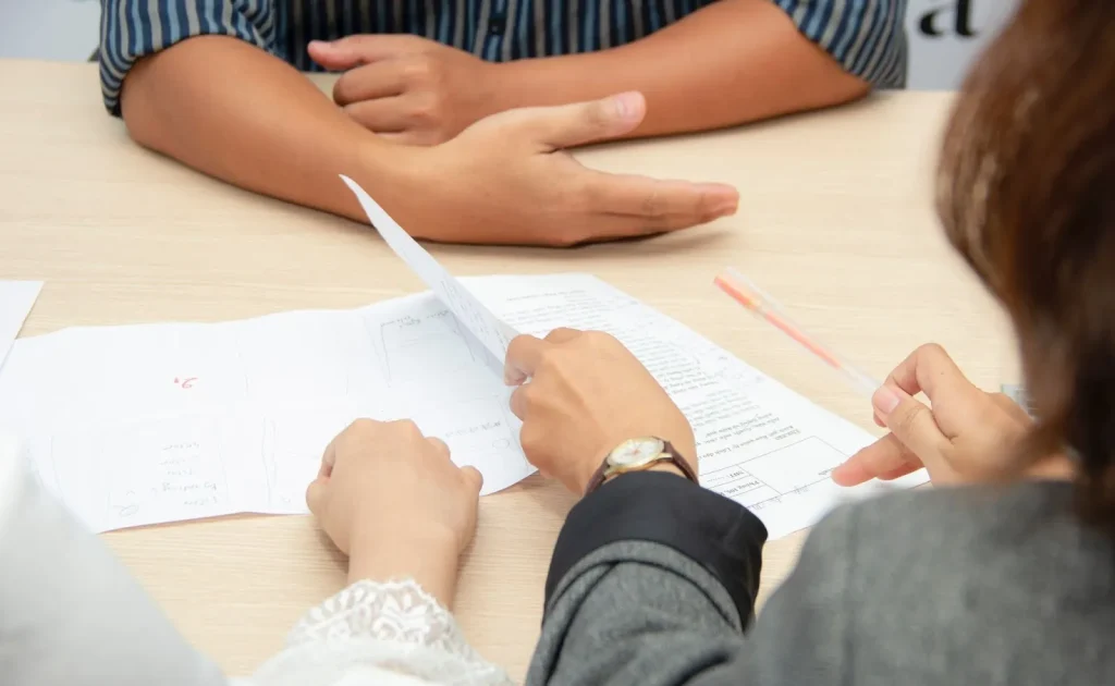 Seseorang sedang menulis draf dokumen di atas kertas.