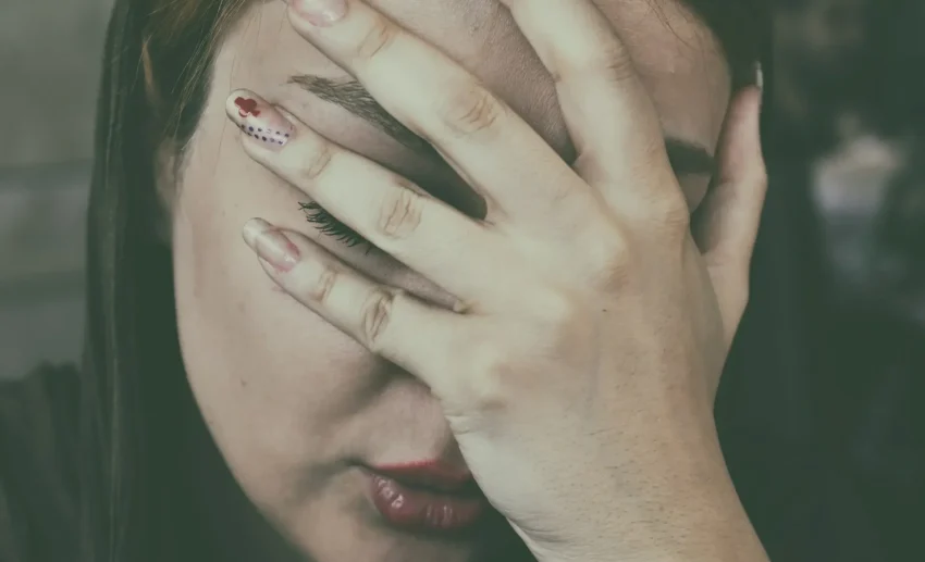 Seseorang terlihat menyesal dan memegang kepalanya di depan laptop.