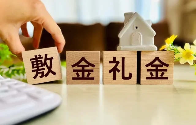 Tangan seseorang menyerahkan uang kertas Yen Jepang, melambangkan pembayaran biaya awal sewa.