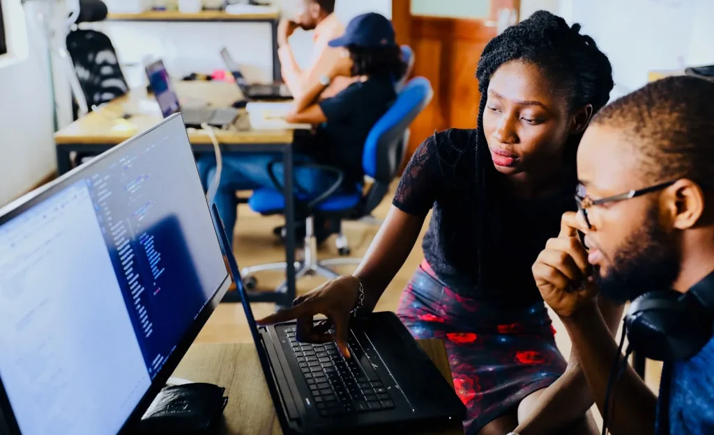 Seorang programmer sedang bekerja di depan beberapa monitor.