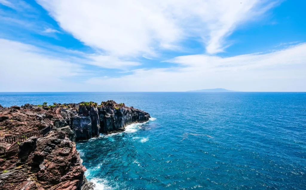 Pemandangan dramatis Pesisir Jogasaki dengan tebing-tebing vulkanik dan lautan biru.