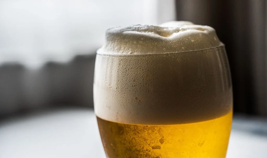 Segelas bir Sango dengan latar belakang pemandangan Okinawa World.