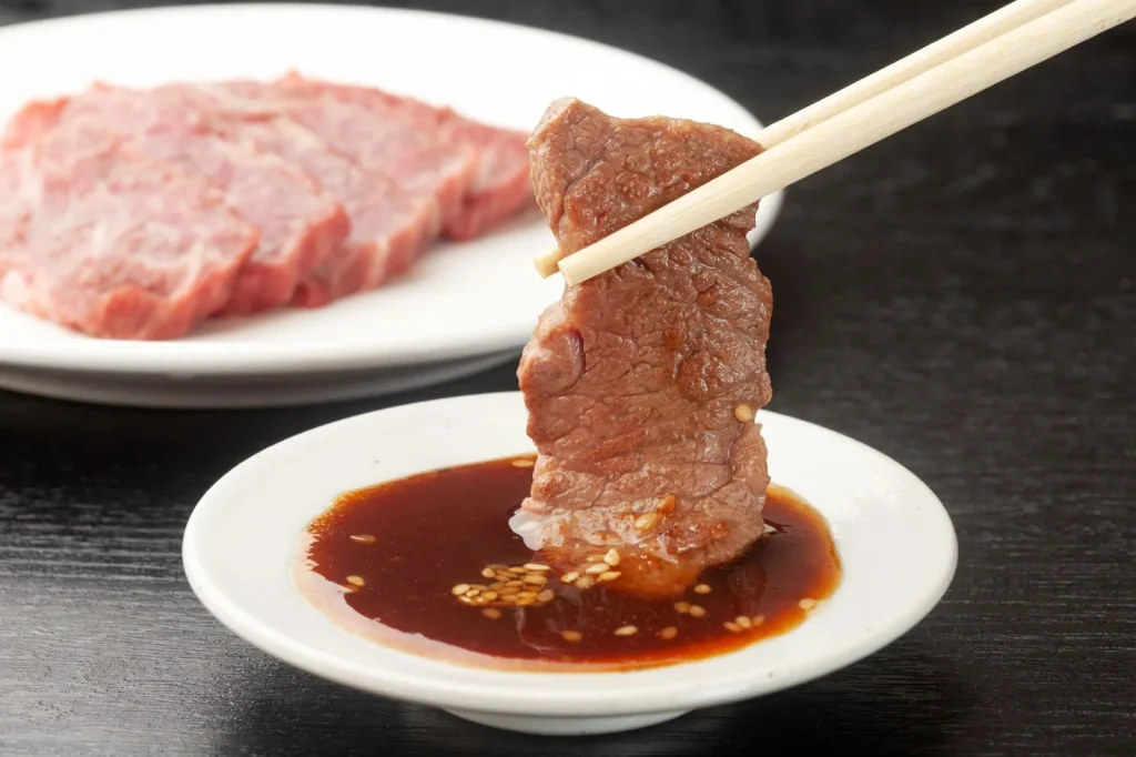 Daging yakiniku yang sedang dipanggang di atas panggangan.