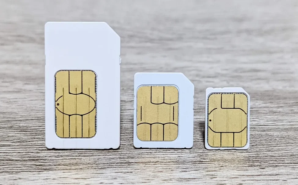 Tangan seseorang sedang memasukkan kartu SIM ke dalam smartphone.