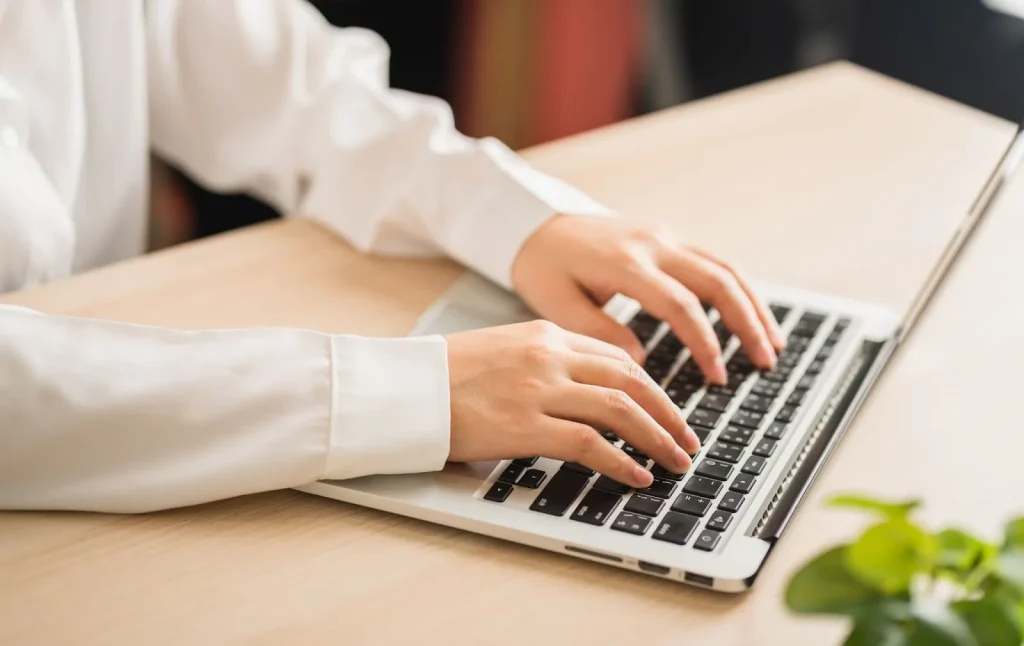 Seseorang sedang mencari lowongan kerja di laptop dengan secangkir kopi.