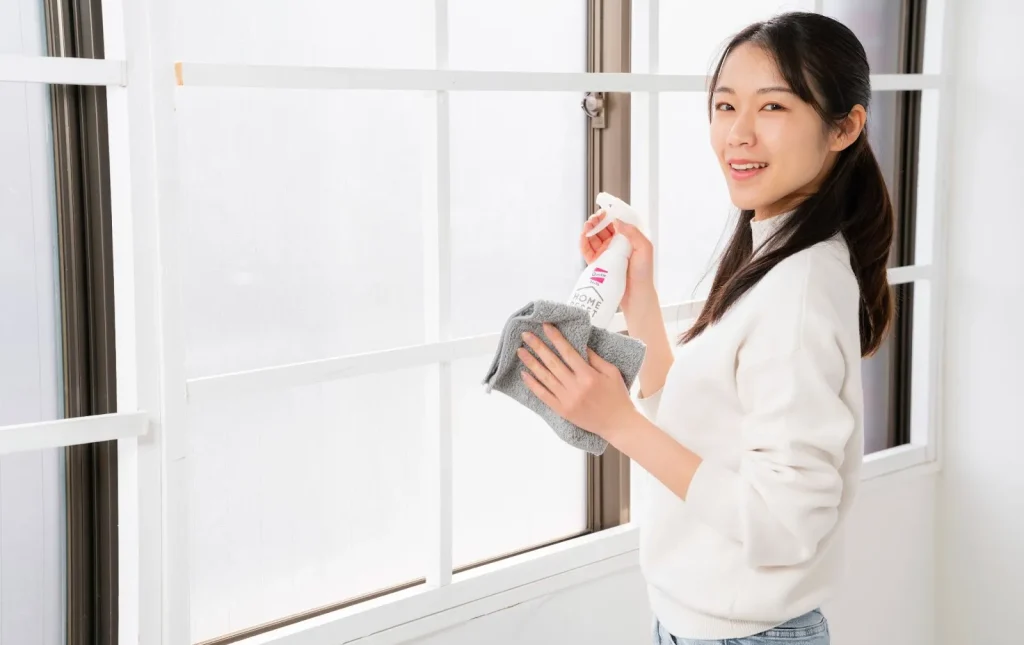 Seorang staf jasa kebersihan sedang membersihkan jendela.