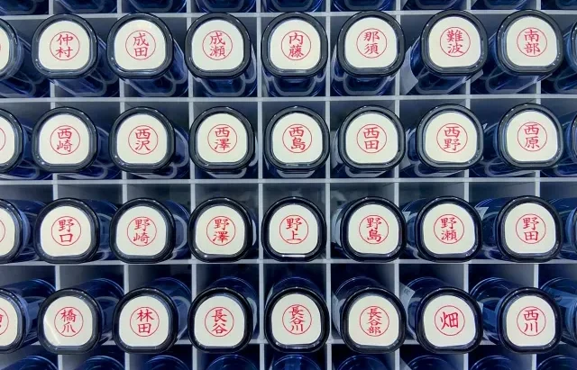 Seorang pengrajin sedang mengukir hanko dengan teliti.