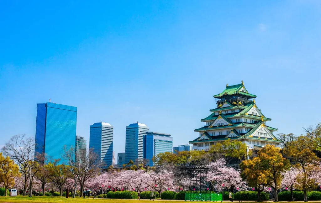 Pemandangan Kastil Osaka yang dikelilingi oleh bunga sakura yang sedang mekar.