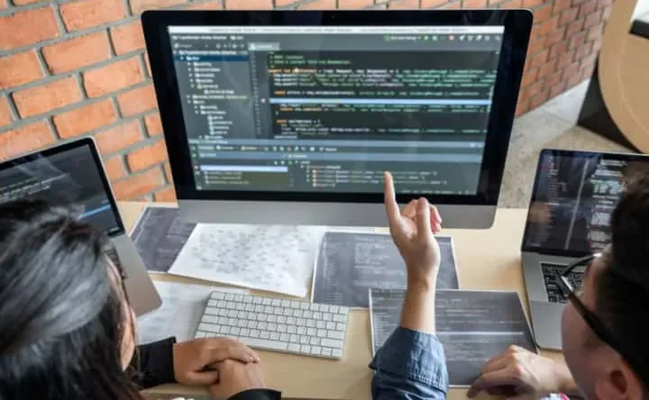 Sekelompok profesional dari berbagai negara sedang bekerja bersama di depan komputer.