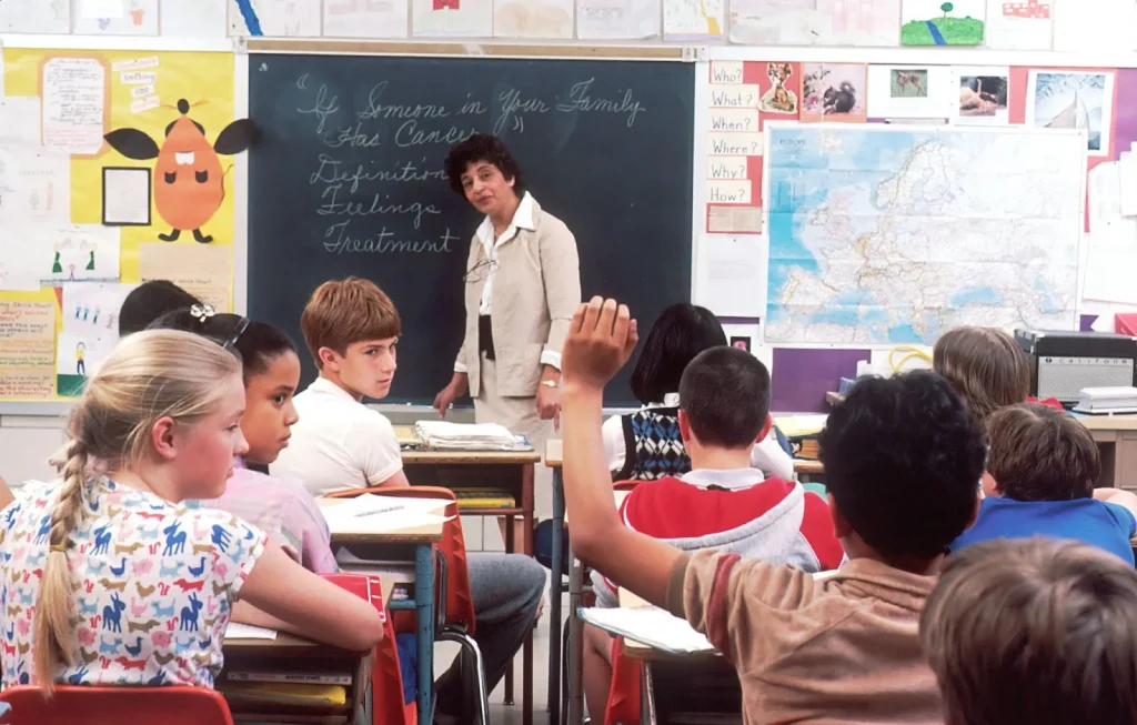 Seorang guru bahasa Inggris sedang mengajar di dalam kelas.