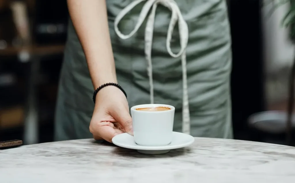 Seorang staf restoran sedang melayani pelanggan dengan ramah.