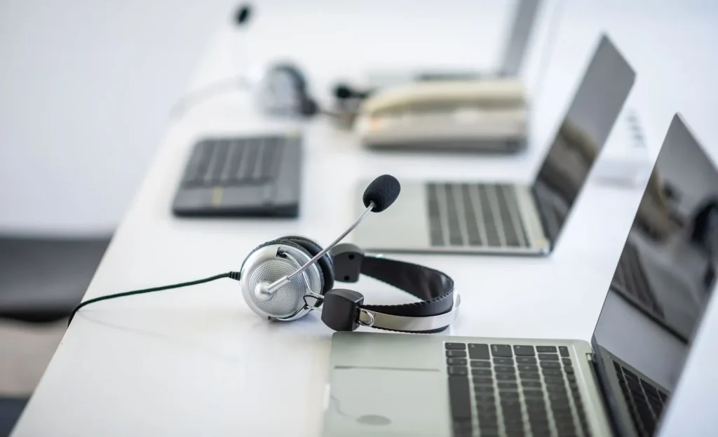 Seorang staf customer service sedang tersenyum sambil menggunakan headset.