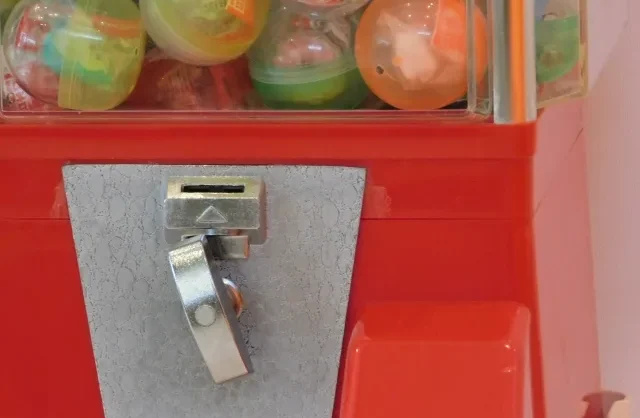 Seorang anak kecil sedang dengan antusias melihat mesin Gachapon.