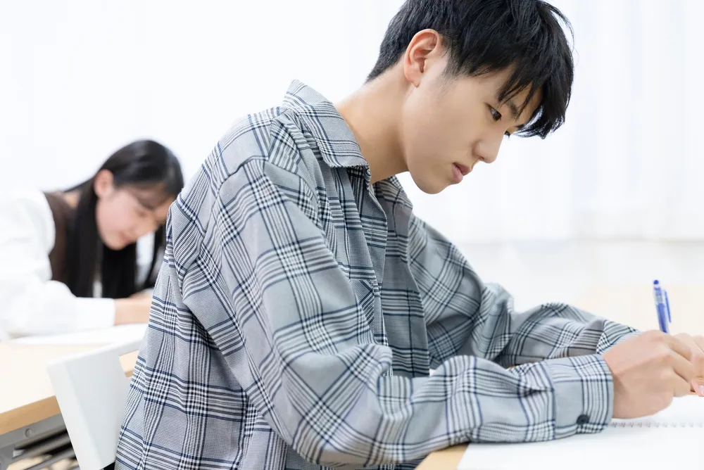 Seorang mahasiswa sedang tersenyum sambil memegang sertifikat kelulusan.