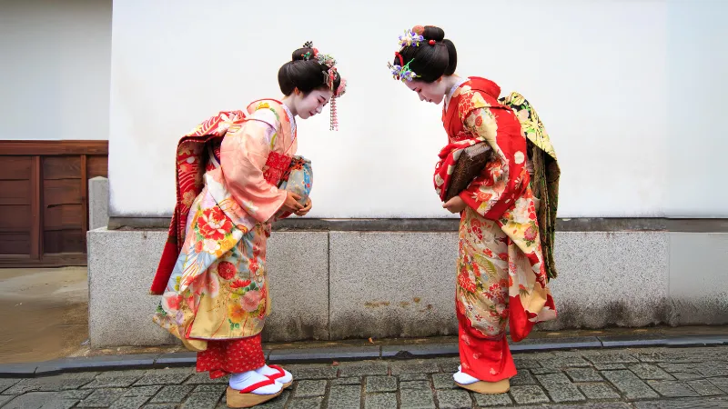 Dua orang pebisnis wanita sedang saling membungkuk.