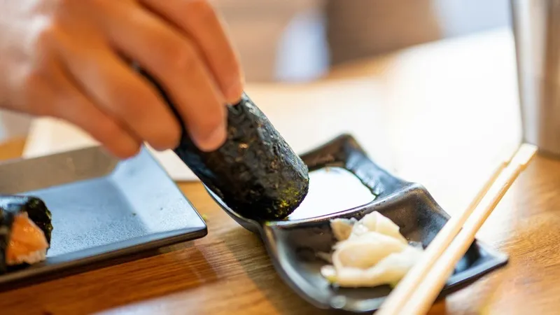 Seorang koki sushi sedang menyiapkan hidangan di depan pelanggan