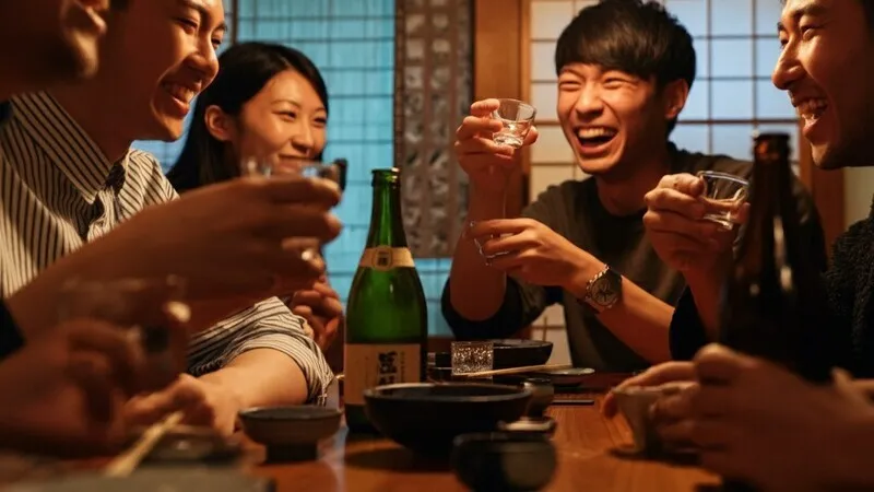 Seseorang sedang menuangkan sake dari tokkuri ke o-choko